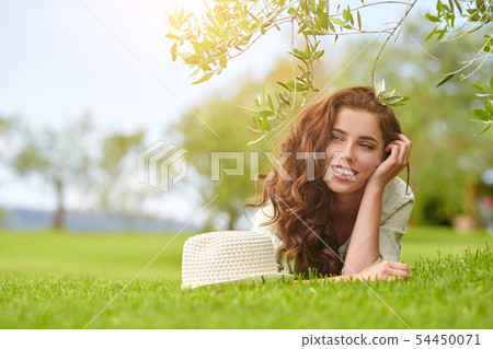 Beautiful smiling woman lying on a grass outdoor. Beautiful smiling woman lying on a grass outdoor. 54450071