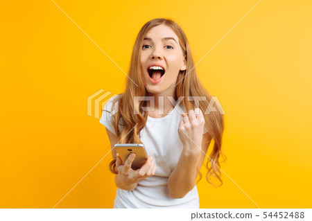 Cheerful girl holding a mobile phone, celebrates Cheerful girl holding a mobile phone, celebrates 54452488