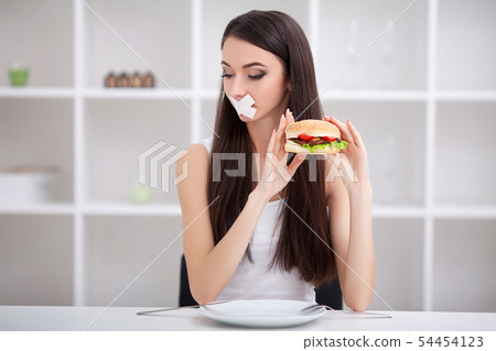 Diet. Close up face of young beautiful sad latin woman with mouth sealed on stick tape Diet. Close up face of young beautiful sad latin woman with mouth sealed on stick tape 54454123