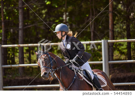 Young woman jockey in white black dress and black Young woman jockey in white black dress and black 54454893