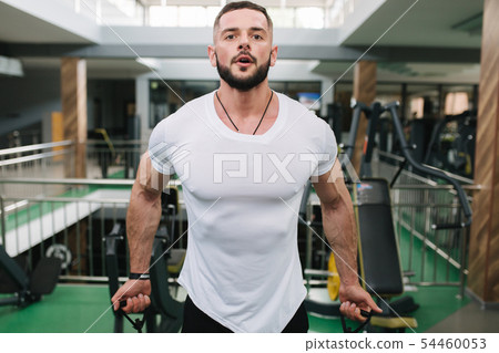 Man use elastic rof training in the gym. Man in white t-shirt trains inside Man use elastic rof training in the gym. Man in white t-shirt trains inside 54460053