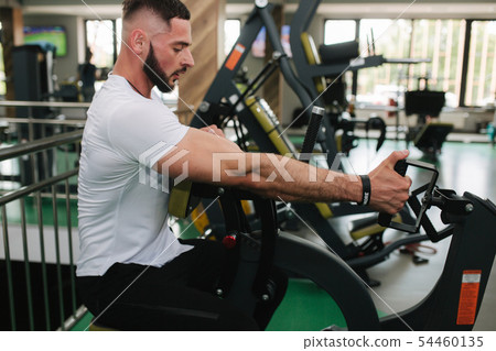A young athlete trains in the gym. Bodybuilder trains the muscules of the back 54460135