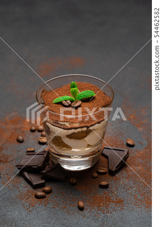 Classic tiramisu dessert with chocolate in a glass on dark concrete background Classic tiramisu dessert with chocolate in a glass on dark concrete background 54462582