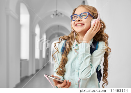 Smiling pretty school girl listening music from headphones. 54463154