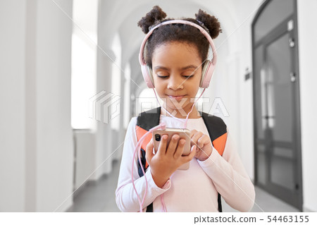 Pretty little African school girl wearing big headphones. 54463155