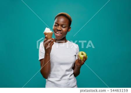 African woman keeping tasty ice cream and healthy apple 54463159
