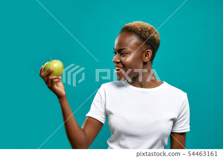 Young woman in white shirt keeping fresh green apple Young woman in white shirt keeping fresh green apple 54463161