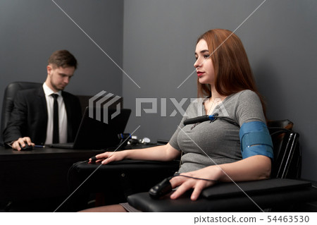 Anxious woman sitting on chair during lie test Anxious woman sitting on chair during lie test 54463530