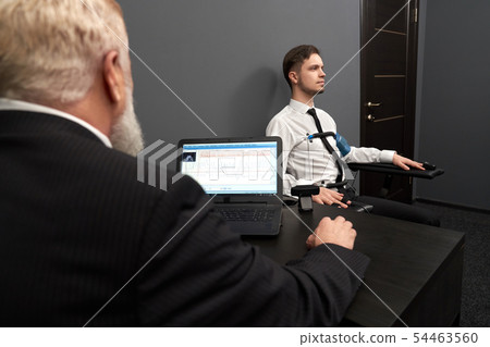 View from back of qualified man in smart suit doing lie test 54463560