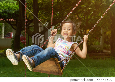 Asian girl smiling on a swing Asian girl smiling on a swing 54464399