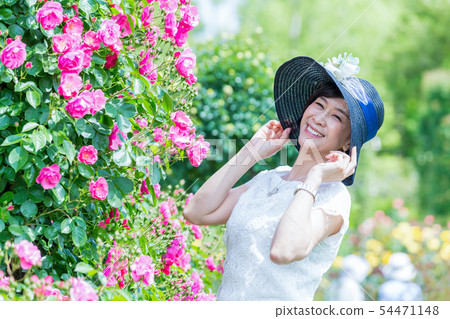 享用玫瑰園的中間婦女在盛開羅斯曲拱玫瑰園 享用玫瑰園的中間婦女在盛開羅斯曲拱玫瑰園 54471148