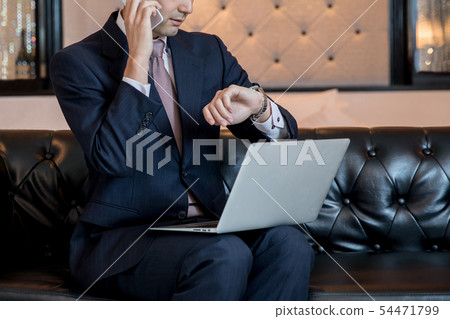 Businessman working while looking at a watch Businessman working while looking at a watch 54471799