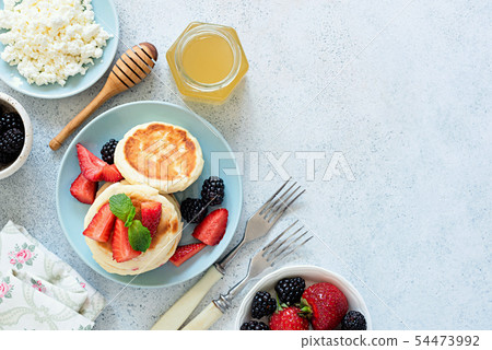 Syrniki, cottage cheese pancakes with berries and honey Syrniki, cottage cheese pancakes with berries and honey 54473992