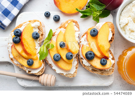 Toast with ricotta cheese, peach, blueberry and honey Toast with ricotta cheese, peach, blueberry and honey 54474089