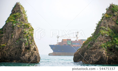 Freighter with multiple containers floats in the sea between the two reefs 54475337
