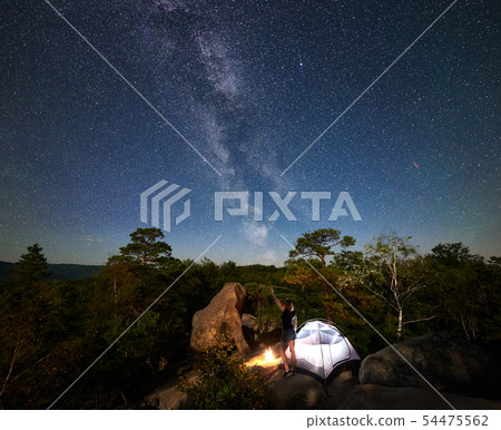 Woman resting beside camp, bonfire and tourist tent at night 54475562