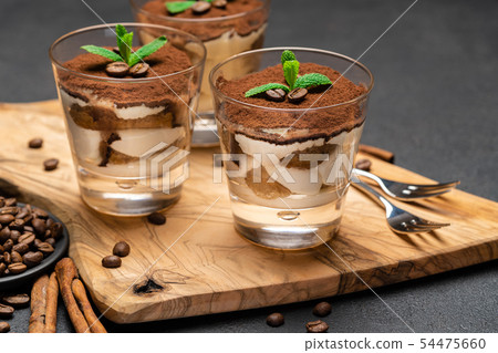 Classic tiramisu dessert with chocolate in a glass no wooden cutting boartd on dark concrete Classic tiramisu dessert with chocolate in a glass no wooden cutting boartd on dark concrete 54475660