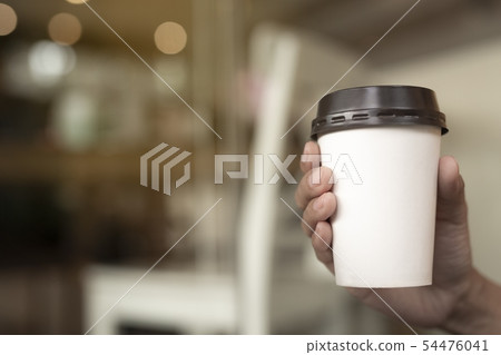 A woman holds a cup of coffee paper. A woman holds a cup of coffee paper. 54476041