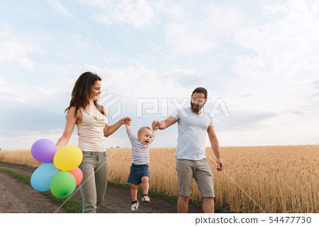 Happy family of mom, dad and son walking outdoors Happy family of mom, dad and son walking outdoors 54477730