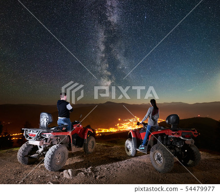 Couple tourists with atv quad bike under night starry sky Couple tourists with atv quad bike under night starry sky 54479977