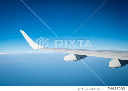 Wing of plane over white clouds. Airplane flying Wing of plane over white clouds. Airplane flying 54485003