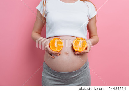 Beautiful pregnant woman with orange fruit on a Beautiful pregnant woman with orange fruit on a 54485514