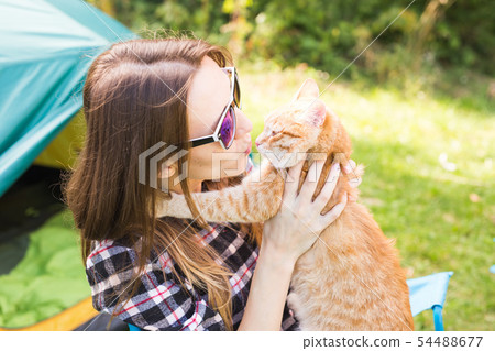 People, tourism and nature concept - Woman in sunglasses holding a cat sitting near the tent People, tourism and nature concept - Woman in sunglasses holding a cat sitting near the tent 54488677