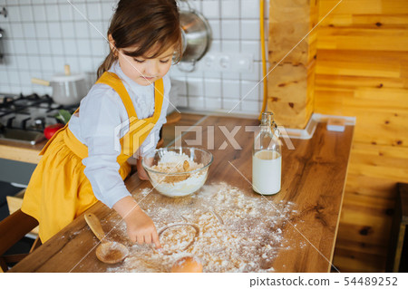Little girl baking a cake in the kitchen. Little girl baking a cake in the kitchen. 54489252