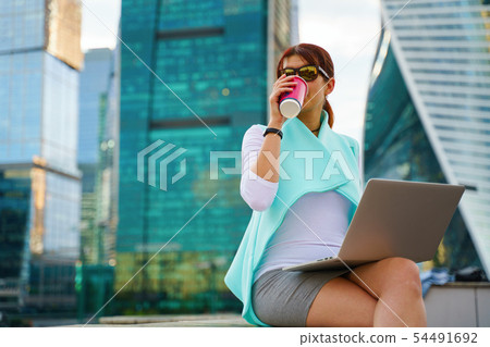 Portrait of business woman sitting with laptop and cup of coffee Portrait of business woman sitting with laptop and cup of coffee 54491692
