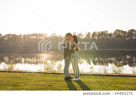 Romantica, nature and people concept - young couple kissing on the beach of lake and hugging Romantica, nature and people concept - young couple kissing on the beach of lake and hugging 54493175