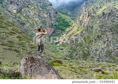 Male hiker takes photo of beautiful mountains in North Caucasus in summer 54496941