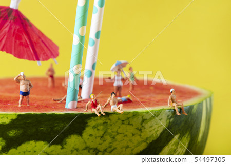 miniature people in swimsuit on a watermelon 54497305