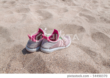 Concept with pink sneakers on bright sea sand. Concept with pink sneakers on bright sea sand. 54498370