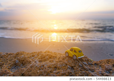 Yellow toy car on the beach in the sunlight in 54498613