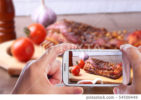 hands of man with smartphone taking photo Grilled pork ribs barbecue Striploin steak with hands of man with smartphone taking photo Grilled pork ribs barbecue Striploin steak with 54500449