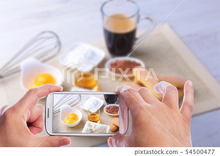 hands of man with smartphone taking photo ingredient for homemade tiramisu cake in close up. Top 54500477