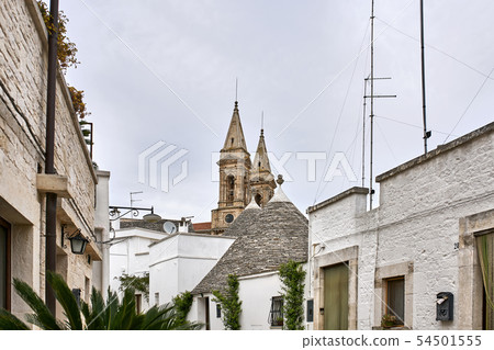 Old trulli houses and medieval basilica in Alberobello town in Italy 54501555