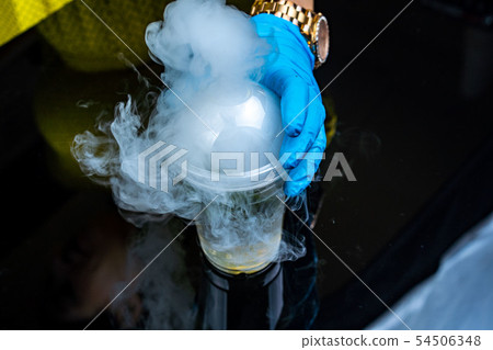 Cocktail with ice vapor on bar desk, close-up. dry ice. 54506348