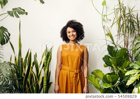 Smiling woman standing at wall in plant shop Smiling woman standing at wall in plant shop 54509829