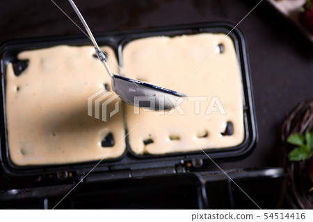 Waffles dough pouring on the baking machine 54514416