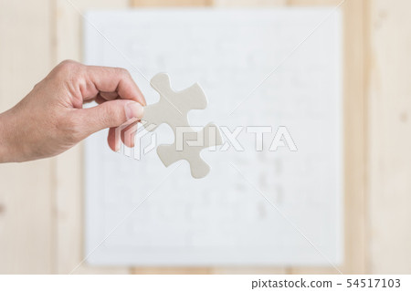 Jigsaw puzzle game piece in person hand on blur  54517103