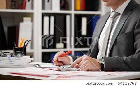 Businessman working and calculating, reads and Businessman working and calculating, reads and 54518768