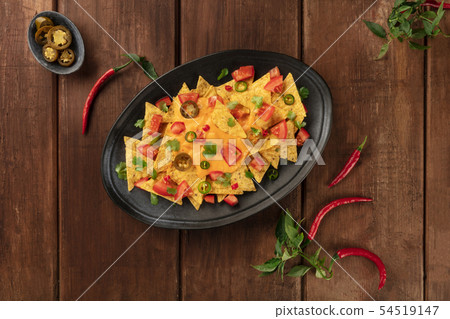 Nachos, Mexican tortilla chips, shot from the top with a cheese sauce, chili and jalapeno peppers 54519147