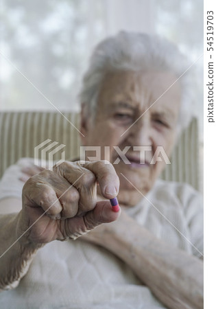 senior woman holding a pill 54519703
