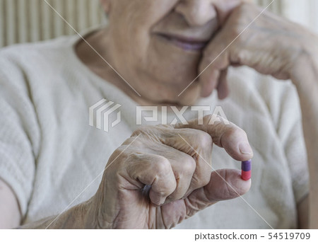 senior person holding a pill 54519709