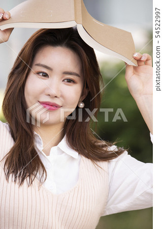 A woman holding a book on her head 54522997