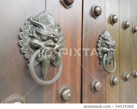 Ancient lion knocker on wooden door Ancient lion knocker on wooden door 54524368