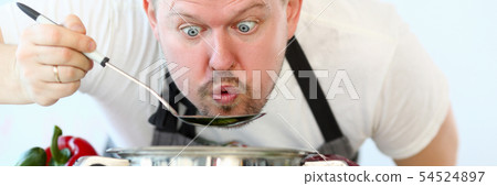 Male cook tries hot soup from pan 54524897