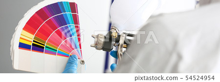 Hands of workman holding airbrush and colorful fantail picking wall tone 54524954