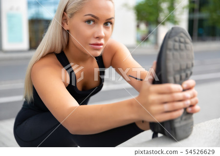 Smiling gorgeous young Woman Doing Stretching Exercise At Sidewalk In City 54526629